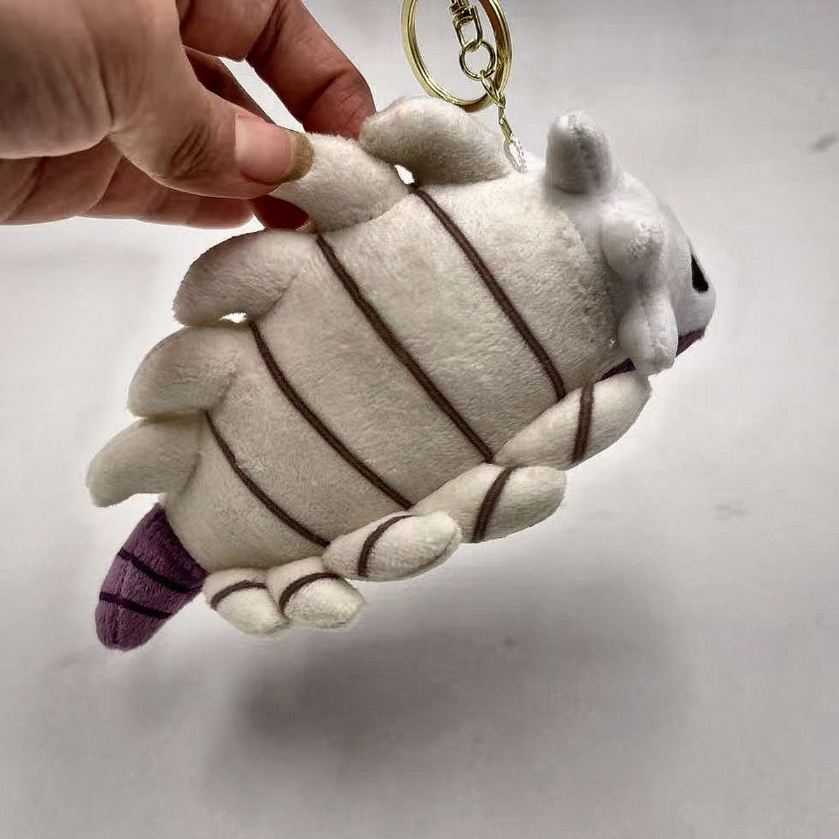Bell Beast plush keychain held in hand for scale
